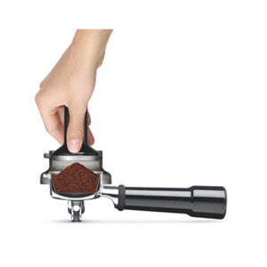 Hand holding a coffee grinder with ground coffee on a white background